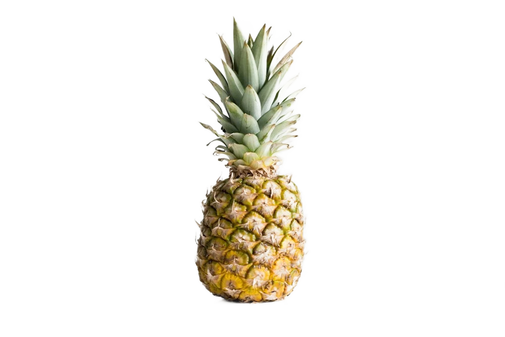 A whole pineapple on a light studio background, background removed